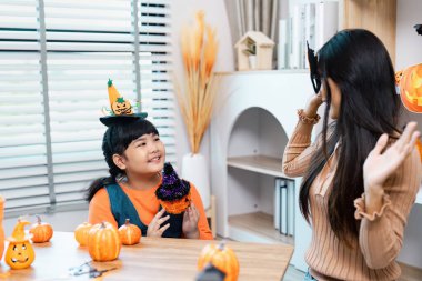 Cadılar Bayramı el işleri ve dekorasyonlarıyla eğlenen, cadı şapkaları takan ve rahat bir yuvada balkabaklarıyla çevrili bir anne ve kız..