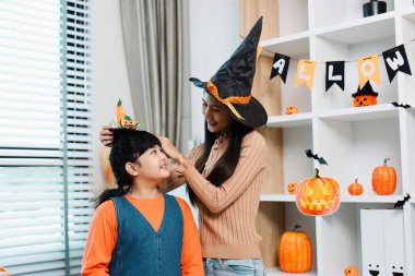 Bir anne ve kız Cadılar Bayramı 'nın tadını çıkarıyor. Etrafı şenlikli dekorasyonlarla çevrili ve cadı kostümleri giyiyor..