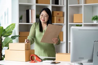 Girişimcilik işini ev ofisinden yönetiyor, paket kutularını düzenliyor ve pano kullanıyor..