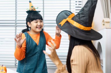 Çocuklar cadılar bayramının tadını içeride çıkarıyorlar, kostümler giyiyorlar ve şenlikli dekorasyonlarla eğlenceli aktivitelere giriyorlar..