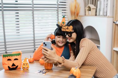 Bir anne ve kız Cadılar Bayramı 'nın tadını çıkarırken evde balkabaklarını süslüyor ve birlikte neşeli anılar yaratıyorlar..