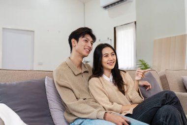 Modern oturma odalarında rahat bir koltukta oturan neşeli bir çift birlikte neşeli bir anı paylaşıyorlar..