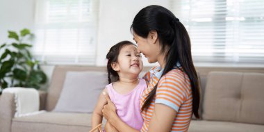 Sevgi dolu bir anne ve küçük kızı aydınlık ve rahat bir oturma odasında keyifli bir anı paylaşıyorlar..