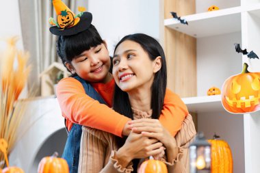 Neşeli bir anne ve kız Cadılar Bayramı 'nı birlikte geçiriyorlar. Etrafı balkabaklarıyla çevrili ve rahat bir ev ortamında şenlikli dekorasyonlarla dolu..