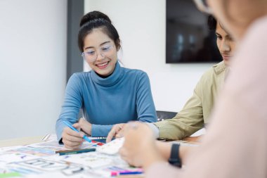 UX UI projesinde birlikte çalışan çeşitli tasarımcılardan oluşan bir ekip çağdaş bir ofis ortamında fikir üretmek ve çizmek için beyin fırtınası yapıyorlar..