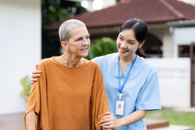 İlgili bir sağlık çalışanı, yaşlı bir hastanın sağlık hizmetlerinde şefkat ve destek göstererek dışarı çıkmasına yardımcı olur..