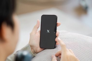 CHIANG MAI, THAILAND - 11 Eylül 2024: iPhone 13 Pro 'da X yeni twitter uygulaması kullanan bir adam. iPhone 13 ekranındaki yeni bir Twitter X uygulama logosunun yakın plan resmi.