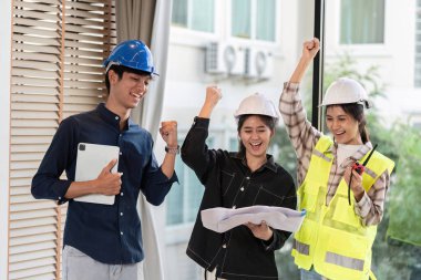 Güvenlik donanımlı üç mühendis, bir inşaat alanında başarılı bir projeyi kutluyor, takım çalışması ve başarı sergiliyorlar..