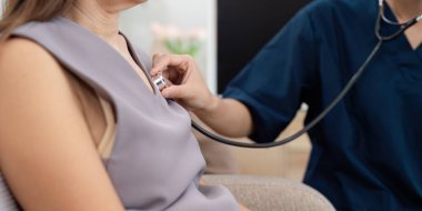 Steteskop kullanan bir sağlık uzmanının tıbbi muayene sırasında hastanın kalp atışlarını dinlemek için yakın plan fotoğrafı..