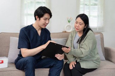 Bir sağlık uzmanı evde yaşlı bir hastaya danışmanlık yapar, tıbbi kayıtları inceler ve bakım sağlar..