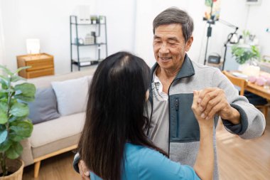Yaşlı bir çift, modern dekor ve doğal ışıkla çevrili oturma odalarında keyifli bir dans eder..