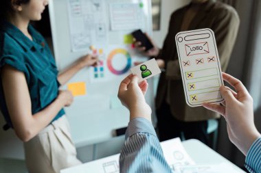 UX UI geliştirme üzerinde işbirliği yapan tasarımcılardan oluşan bir ekip mobil bir uygulama arayüzü için beyin fırtınası oturumları ve prototip oluşturulmasını gösteriyor.