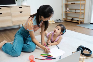 Neşeli bir anne-kız renkli aktivitelerle kaynaşıyor, rahat, modern bir oturma odasında..