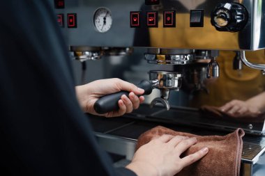 Profesyonel kahve makinesi kullanarak espresso yapan bir baristanın yakın çekimi modern bir kafede kahve hazırlama sanatını gözler önüne seriyor..