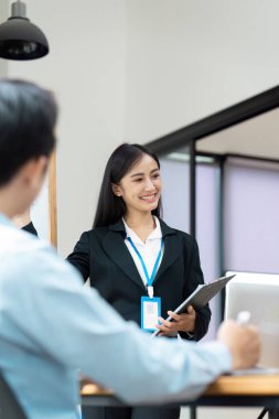 Takım elbiseli kendine güvenen bir iş kadını modern ofis ortamında meslektaşlarına sunuyor, takım çalışması ve işbirliği sergiliyor..