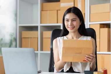 Genç bir girişimci, çevrimiçi olarak küçük işletme ürünleri satma kavramını temsil eden bir paket hazırlar..