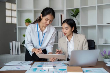 Çeşitli takımlar modern bir ofiste işbirliği yapıyor, finansal raporları analiz ediyor ve proje stratejilerini tartışıyorlar..