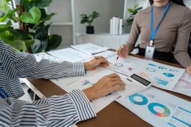 Modern ofis ortamında yapılan bir iş toplantısında finansal tabloları ve verileri analiz eden profesyoneller.