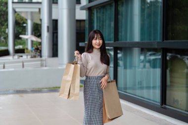 Woman with shopping bags enjoying Black Friday deals outside a contemporary shopping center. clipart