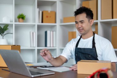 Küçük bir işletme sahibi, çevrimiçi siparişleri, ambalaj kutularıyla çevrili, modern bir ofis ortamında işler..