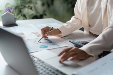 Finansal çizelgeleri ve grafikleri modern bir ofiste dizüstü bilgisayarla inceleyen bir iş adamının yakın çekimi..