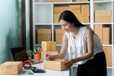 Genç girişimci küçük bir işletme ofisinde sevkiyat için paketler hazırlıyor. E-ticaret, başlangıç ve çevrimiçi perakende satış kavramları için ideal.