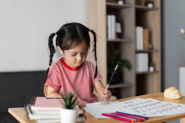 Eğitimsel materyallerle çevrili, bir evde yaratıcılığı ve bilgiyi destekleyen, öğrenmeye odaklanmış küçük bir çocuk.