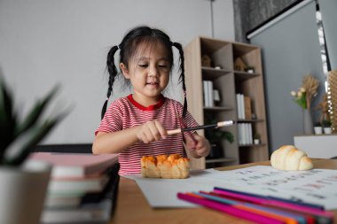 Genç bir çocuk, kitap ve sanat malzemeleriyle öğrenmeyi, yaratıcılığı ve eğitimi rahat bir evde teşvik etmeyi keşfediyor..