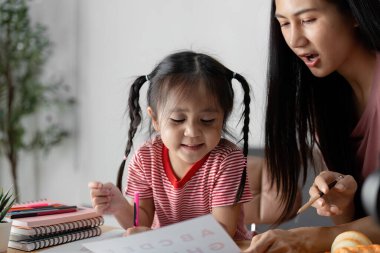Küçük bir çocuk, sıcak bir yuva ortamında eğitim materyalleriyle çevrili ebeveyniyle hevesle öğrenir..