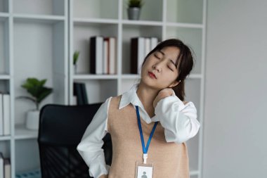 Genç bir profesyonel ofis sendromu nedeniyle boyun ağrısından muzdarip olup, modern ofis ortamında ergonomi sorunlarını vurguluyor..