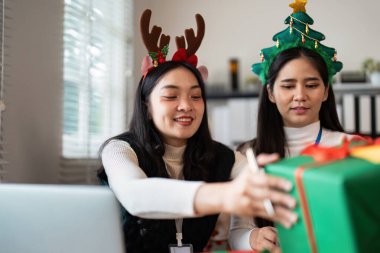 Noel kutlamasının tadını çıkaran arkadaşlar tatil süslemeleri ve neşeli atmosferi olan rahat bir evde hediye alışverişi yapıyorlar..