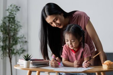 Bir anne ve kız evde eğlenceli bir çizim faaliyeti içinde, yaratıcılığı teşvik ediyor ve sıcak bir oturma odasında bağ kuruyor..