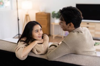 Genç bir çift şık, modern bir oturma odasında rahat bir kanepede huzurlu bir anın tadını çıkarıyor..