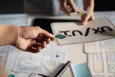 UX UI tasarımı üzerinde çalışan eller, dijital arayüzler için yaratıcı süreci gösteren kablolar ve prototipler üzerinde çalışıyor.