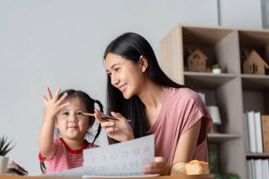 Ebeveyn ve çocuk evde eğlenceli bir öğrenme oturumunun keyfini çıkarıyor, eğitimi ve aile bağlarını destekliyor.