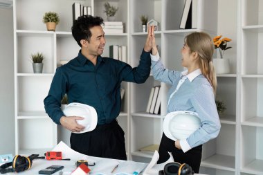 Modern ofis ortamında mimari planları, takım çalışmasını ve yenilikleri tartışan iki mühendis..