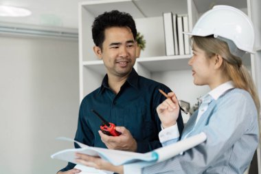 Modern ofis ortamında mimari tasarımlar, takım çalışması ve yenilik üzerine işbirliği yapan mühendisler.