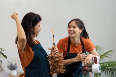 İki kadın evlerini modern aletlerle mutlu bir şekilde temizliyor, parlak ve düzenli bir ortamda takım çalışması ve verimlilik sergiliyorlar..