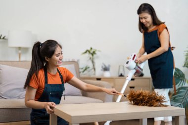 Temizlikçi modern bir evi etkin bir şekilde temizliyor, temiz bir yaşam alanı için süpürge ve toz alma teknikleri sergiliyor..