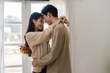 Sevgi dolu bir çift, güneşli bir odada sıcak ve samimi bir atmosfer yaratarak samimi bir kucaklaşmayı paylaşır..