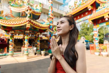 Çin Yeni Yılı 'nı kutlayan bir kadın renkli bir tapınakta kültürel gelenekleri gezer ve benimser..