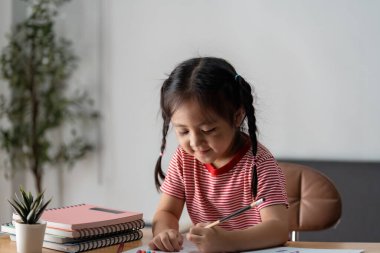 Eğitimsel büyüme ve aile bağlarını bir ev ortamında vurgulayan, ebeveyniyle öğrenim faaliyetlerine katılan bir çocuk.