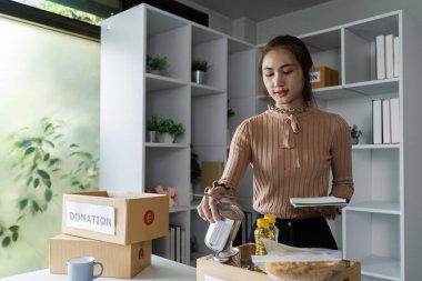 Adanmış yardımcılar bir gıda bankasına bağış ayırıyor, toplum desteği ve takım çalışması sergiliyor.