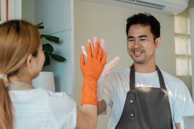 Modern bir ev ortamında temizlik, vitrin ve pozitiflik yaparken iki kişi beşlik çakıyor..