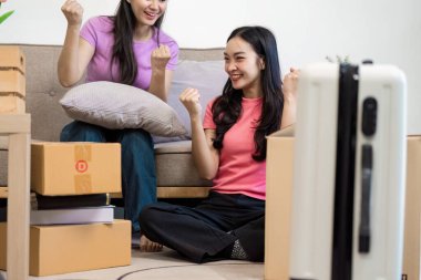 İki kadın, yeni yaşam alanlarında kutuları açarken heyecan ve neşeyi ifade eder. Hareketlerini gülümseme ve tezahüratla kutlarlar..