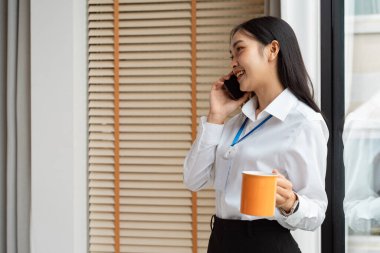 Bir iş adamı kahve fincanı tutarken bir telefon görüşmesi yapıyor, kurumsal bir ortamda etkili bir iletişim ve iletişim sağlıyor..