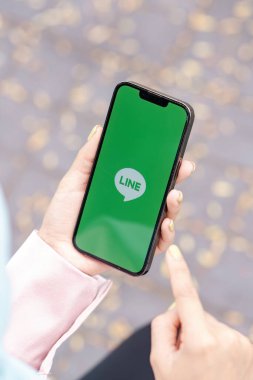 CHIANG MAI, THAILAND - 27 Ocak 2026: Apple iPhone 'u açık ekrana bağlayan kadın. LINE ücretsiz sesli arama yapmanızı ve ücretsiz mesaj göndermenizi sağlayan yeni bir iletişim uygulaması