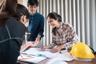 Bir grup inşaat uzmanı ayrıntılı plan ve planları gözden geçirirken, takım çalışmalarını ve proje geliştirme çalışmalarını ön plana çıkardılar.