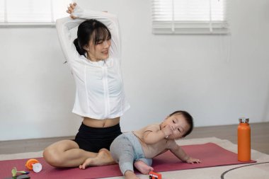 Aktif bir anne, bebeği yakınlarda keşfederken esniyor, sağlıklı ve sağlıklı bir yaşam sürüyor..