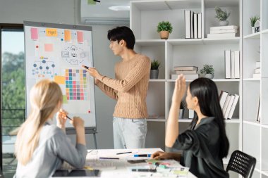 Bir UX UI tasarım oturumu sırasında beyaz tahtada fikirler sunan bir tasarımcı, işbirlikçi bir çalışma alanında ekip beyin fırtınası ve görsel planlamayı teşvik ediyor.